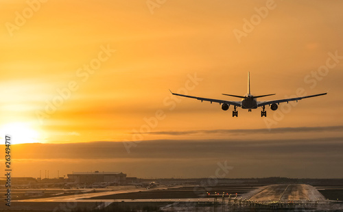 Airplane landing to airport runway in sunset