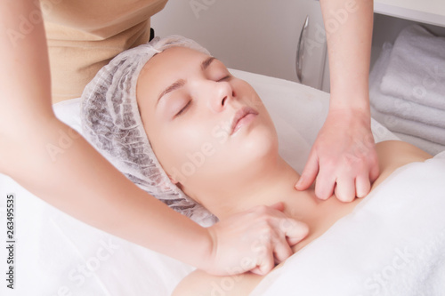 Closeup of young woman receiving shoulders and neckline massage from massage therapist.