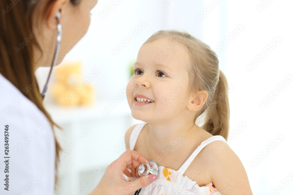 Doctor examining a little girl by stethoscope. Happy smiling child patient at usual medical inspection. Medicine and healthcare concepts Doctor examining a little girl by stethoscope. Happy smiling child patient at usual medical inspection. Medicine and healthcare concepts