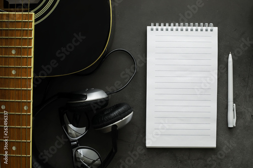 Guitar and accessories on a stone background. Desk musician, headphones, microphone. photo