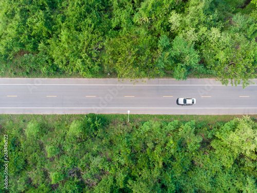 Aerial view of the road passing the forest  with a car passing by