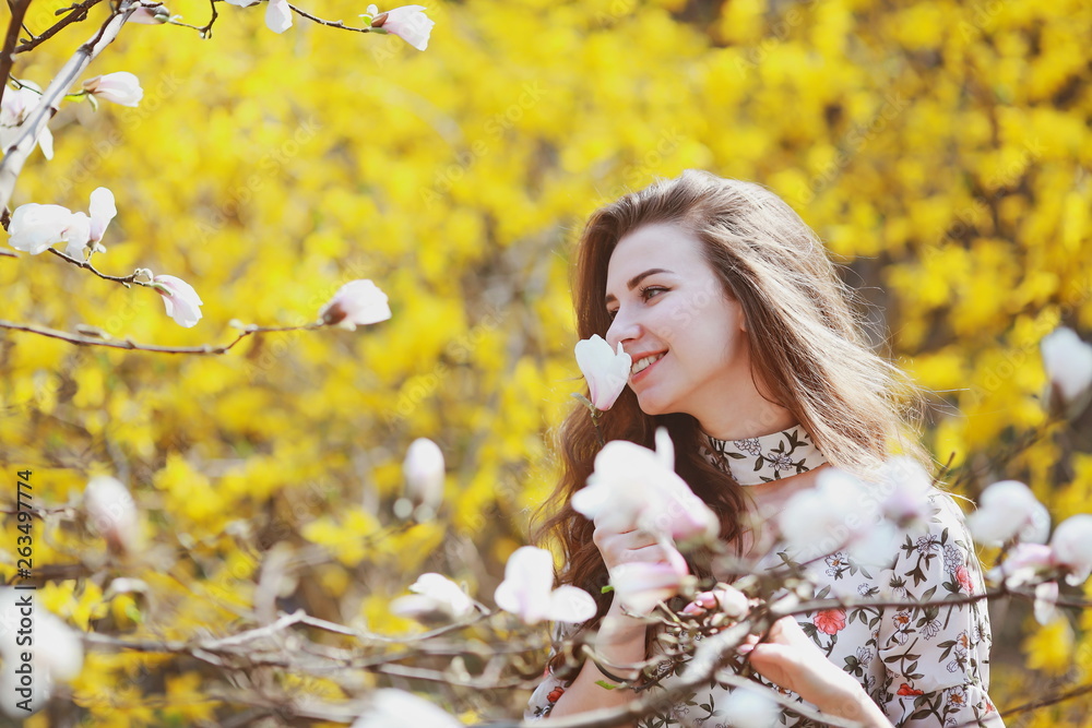 Naklejka premium beautiful young woman sniffing a flowering tree in the garden
