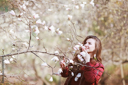 beautiful young woman sniffing a flowering tree in the garden