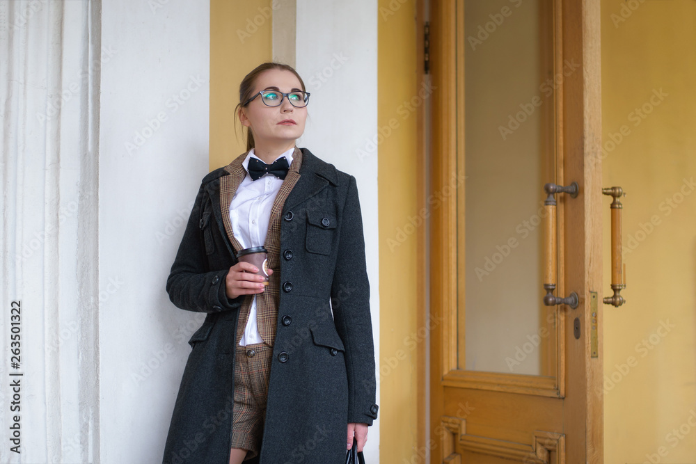 girl in a stylish suit drinks coffee from a paper cup. girl in a stylish suit drinks coffee from a paper cup.