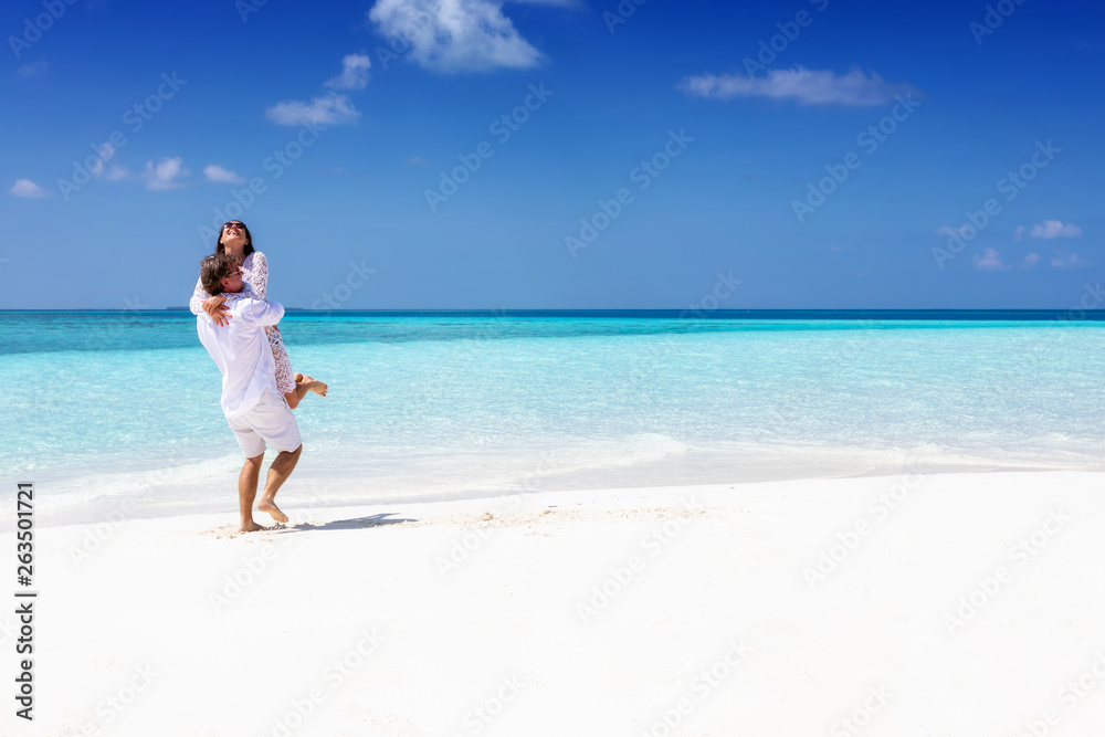 Glückliches Liebespaar in weißen Sommerkleidern genießt den tropischen Strand auf den Malediven Glückliches Liebespaar in weißen Sommerkleidern genießt den tropischen Strand auf den Malediven