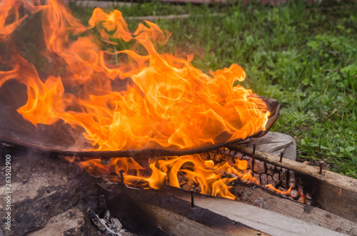 Fried bbq potatoes in a large frying pan on an open fire with smoke.