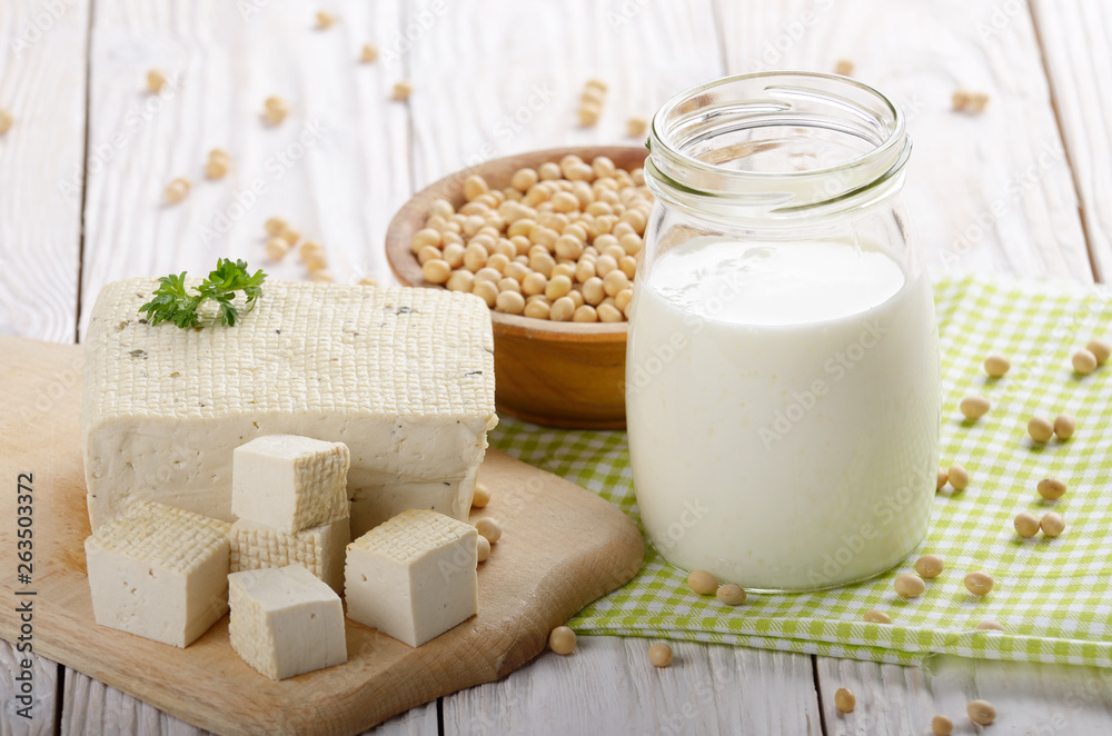 Non-dairy alternatives Soy milk or yogurt in mason jar and tofu on white wooden table with soybeans in bowl aside Non-dairy alternatives Soy milk or yogurt in mason jar and tofu on white wooden table with soybeans in bowl aside