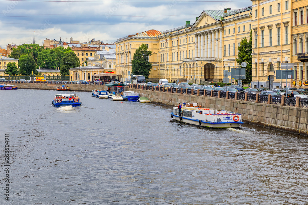 Obraz premium Waterfront buildings on the banks of river Neva and tourist boats on the water in Saint Petersburg