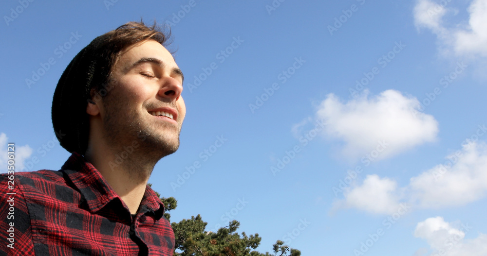 Portrait of an authentic and genuine hipster man smiling on a blue sky with white clouds background. Portrait of an authentic and genuine hipster man smiling on a blue sky with white clouds background.