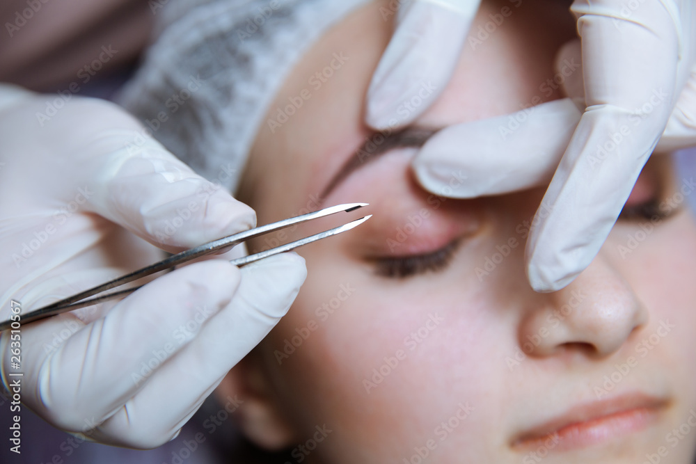 Naklejka premium Process of making eyebrows. Pretty woman with closed eyes on the procedure