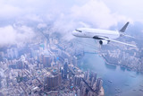 Passenger plane fly to Hong Kong Island. Aerial view at cityscape. Airplane over urban skyline. Concept of travel and air transportation.
