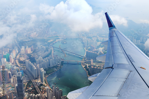 Wallpaper Mural Airplane flies over Hong Kong. Passenger jet plane flying above urban scene. Hongkong flight. Asian destination. Torontodigital.ca