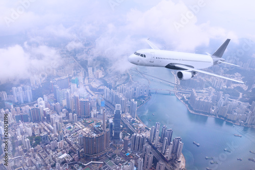 Passenger plane fly to Hong Kong Island. Aerial view at cityscape. Airplane over urban skyline. Concept of travel and air transportation.