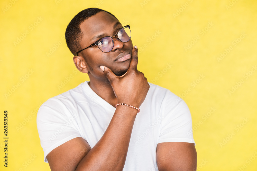 Embarrassed unsure African American man with glasses holds his chin and  purses his lips, looks incredulously, tries to make a decision. Photos |  Adobe Stock