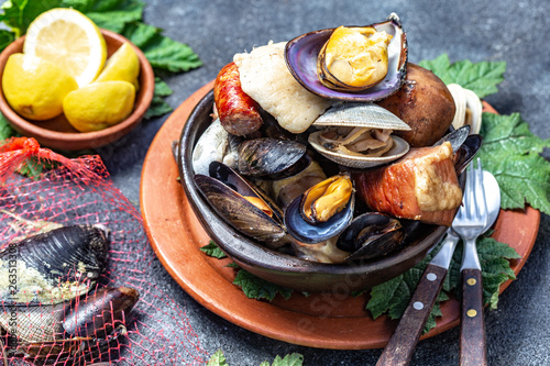 Famous traditional dish of the south of Chile and the Chiloe archipelago - Curanto al Hoyo, Kuranto.  Different seafood,  meat and potatoes milcao cooked in a pit on the coals under the ground photo