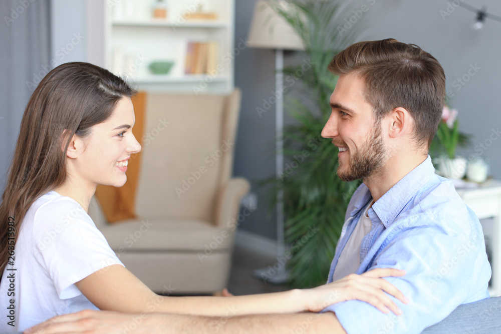 Side view of a couple talking sitting on a couch and looking each other at home. Side view of a couple talking sitting on a couch and looking each other at home.
