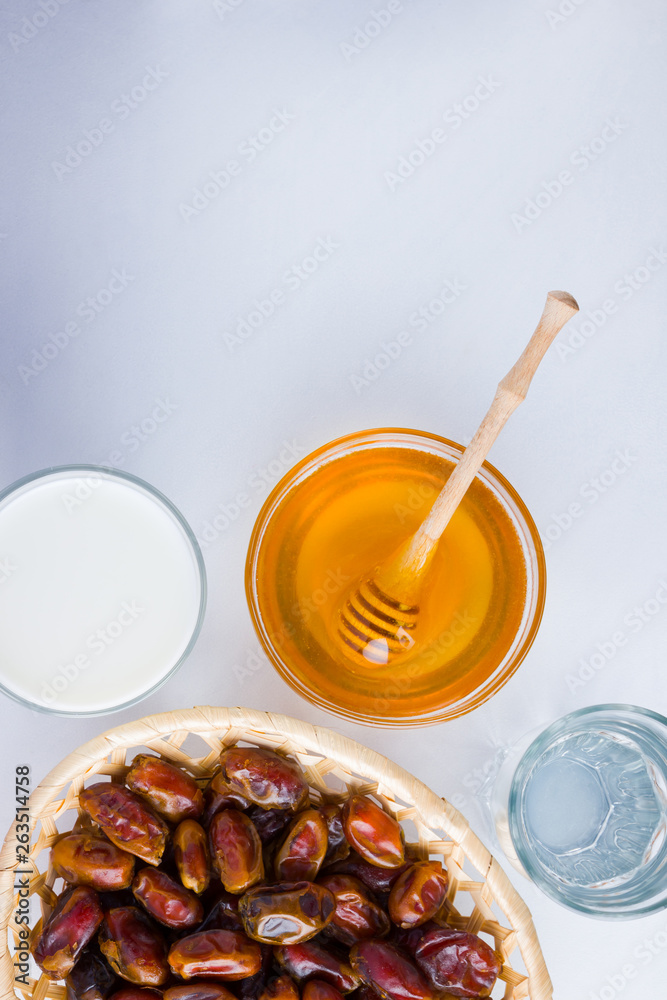 Dried dates, milk and honey on white background. Holy month of Ramadan, concept. Righteous Muslim lifestyle. Starvation. Dates in wooden basket and honey. Vegetarian food. Copy space Dried dates, milk and honey on white background. Holy month of Ramadan, concept. Righteous Muslim lifestyle. Starvation. Dates in wooden basket and honey. Vegetarian food. Copy space