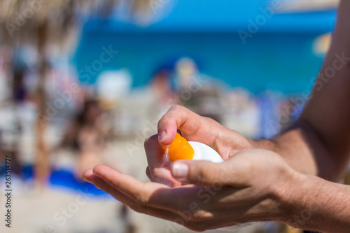 Man hand apply sunscreen on the beach