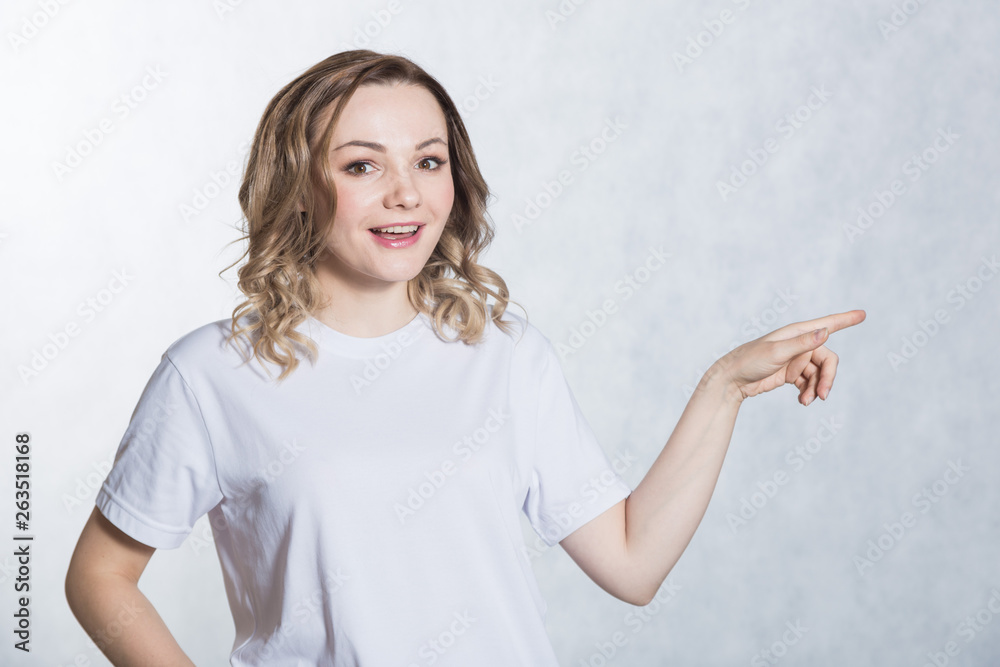 Handsome young woman indicates with forefinger at blank copy space. Handsome young woman indicates with forefinger at blank copy space.