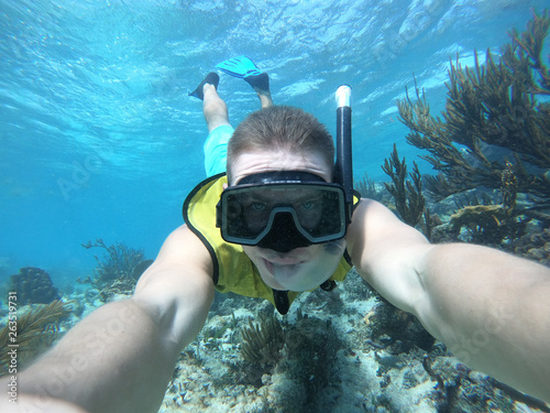 Underwater wide angle selfie of swimmer in a crystal water with marina life