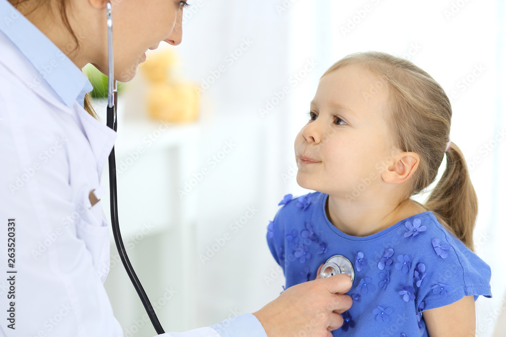 Doctor examining a little girl by stethoscope. Happy smiling child patient at usual medical inspection. Medicine and healthcare concepts Doctor examining a little girl by stethoscope. Happy smiling child patient at usual medical inspection. Medicine and healthcare concepts