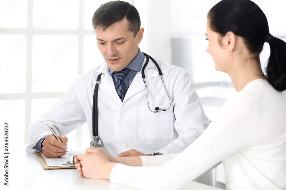 Doctor and patient discussing medical exam resoults at hospital office. Physician using clipboard for filling up medication history records. Perfect medical service in clinic. Medicine and healthcare Doctor and patient discussing medical exam resoults at hospital office. Physician using clipboard for filling up medication history records. Perfect medical service in clinic. Medicine and healthcare