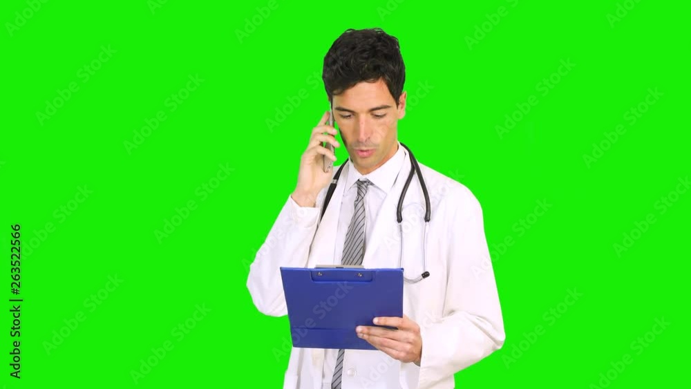 Young doctor on the phone reading a case history, chroma key Young doctor on the phone reading a case history, chroma key