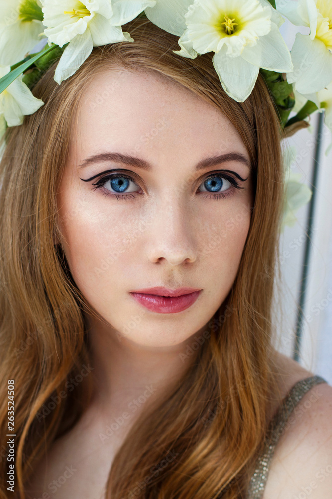Portrait of a tender girl in a wreath of narcissus, spring freshness, light background ..