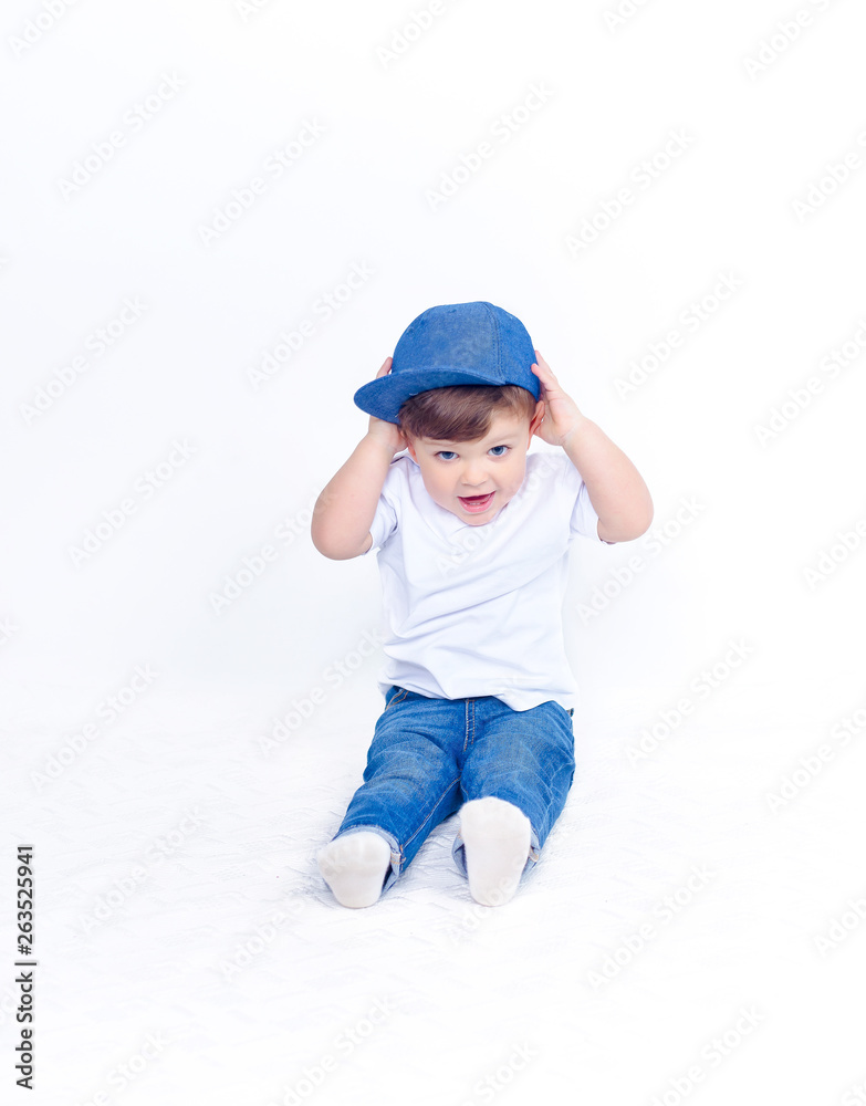 Cute baby in blue jeans, white t-shirt and denim baseball cap sits isolated  on white background Stock Photo | Adobe Stock