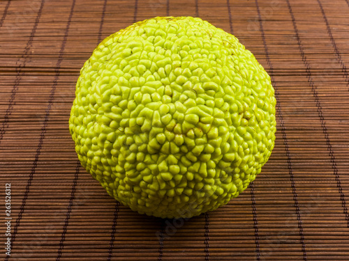 Green fruit of maclura pomifera, osage orange, horse apple, adam apple grow on bamboo mat photo