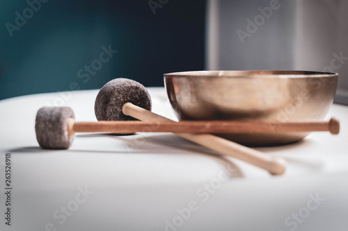 Bronze singing bowl with felt clapper on white sheet for meditation or massage