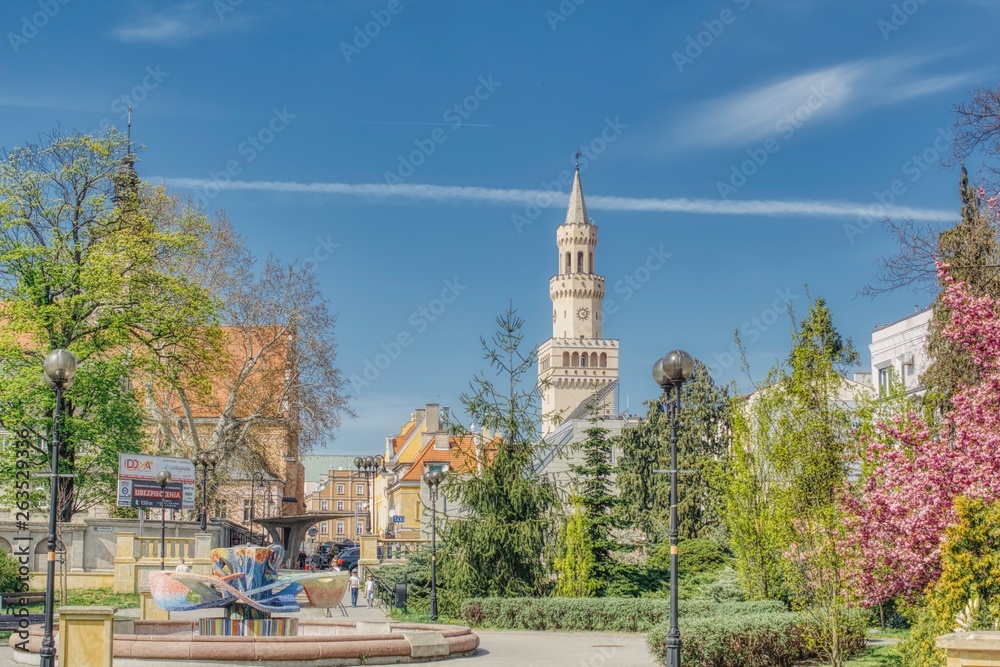 Wiosna w Opolu, plac miejski i ratusz, wiosenne kolory na placu miejskim, zasłonięty kościół franciszkanów, widoczna wieża neorenesansowego ratusza z tarczą zegarową