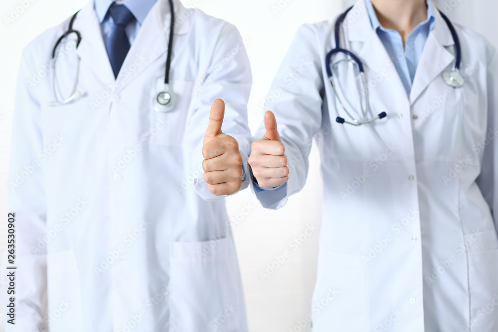 Team of unknown medicine doctors showing OK sign with thumb up close up. Success and high level service in health care, best treatment and customer loyalty and physical concept Team of unknown medicine doctors showing OK sign with thumb up close up. Success and high level service in health care, best treatment and customer loyalty and physical concept