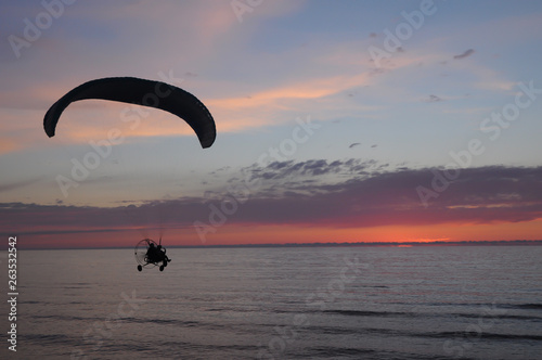 Paraglider at sunset flying over the sea