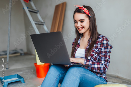 Young woman with laptop doing repairs at new home! Internet helping for decorationA! photo