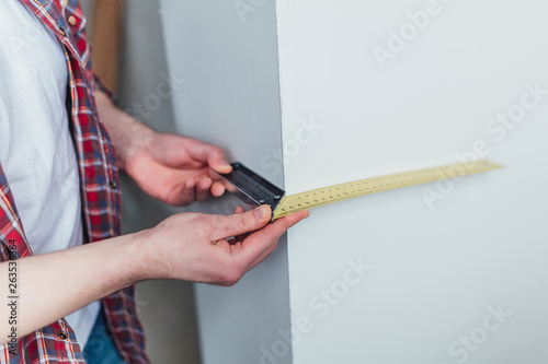 Man is holding a ruler, a belt hanging tools and measure yhe wall. Instrumet concept! photo