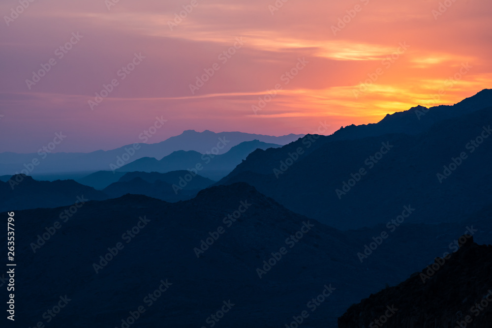 Sunset light glows over a mountain range in Northern Arizona just outside of Sedona. The orange and purple tones give a pleasing, natural contrast to the amazing silhouetted rocky high desert scene. Sunset light glows over a mountain range in Northern Arizona just outside of Sedona. The orange and purple tones give a pleasing, natural contrast to the amazing silhouetted rocky high desert scene.