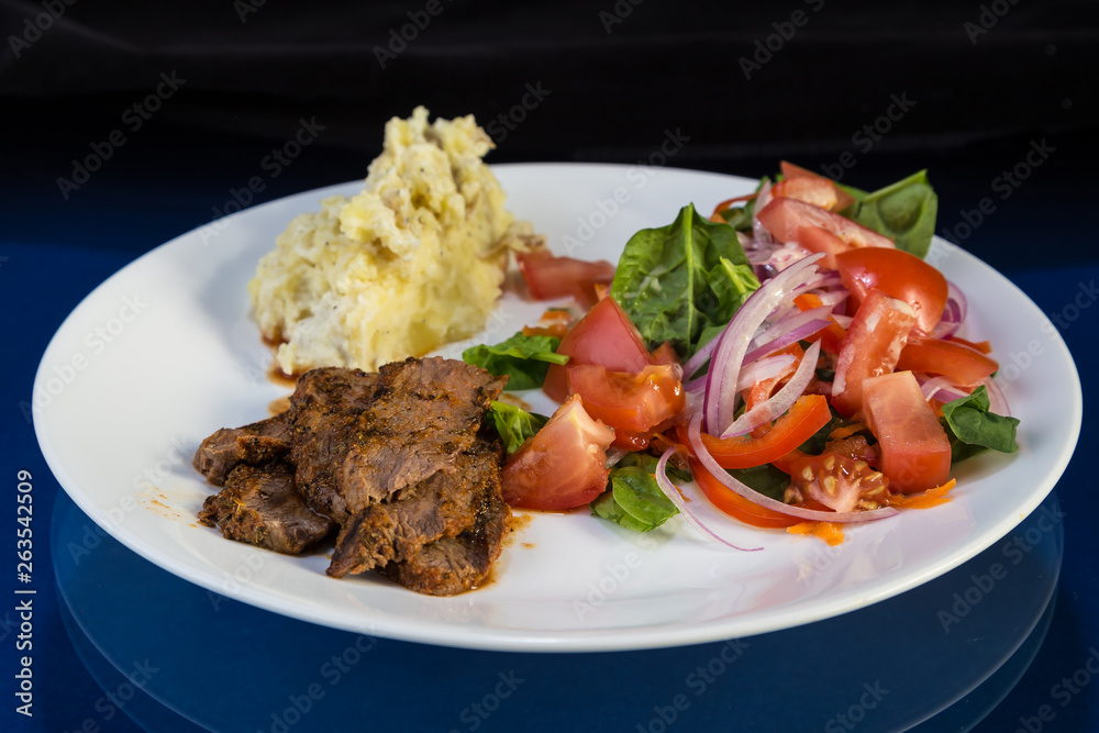 BBQ Beef Brisket on White Plate with Potatoes and Salad against Reflective BG BBQ Beef Brisket on White Plate with Potatoes and Salad against Reflective BG