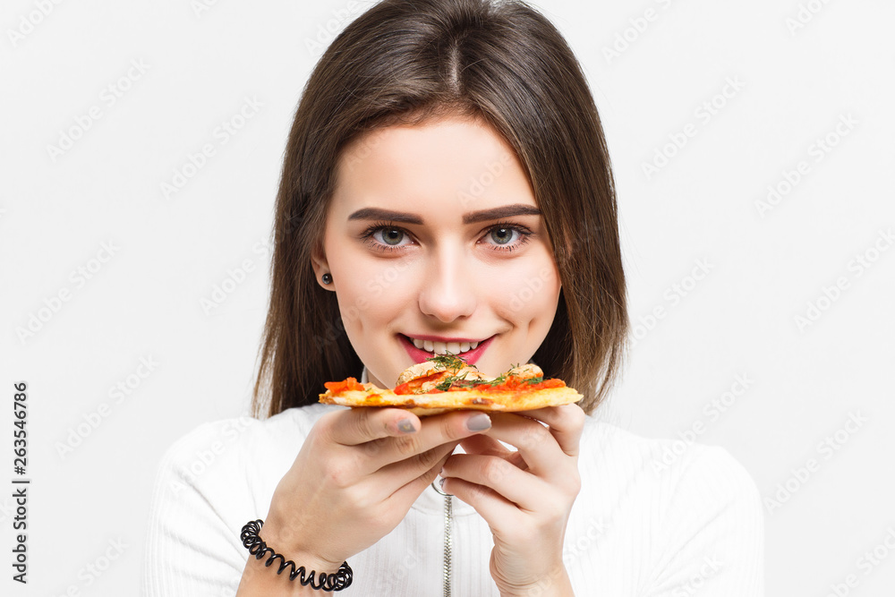 Mmm, so delicious! Dark haired pretty woman eats slice of Italian pizza, enjoys nice taste, isolated over white background.