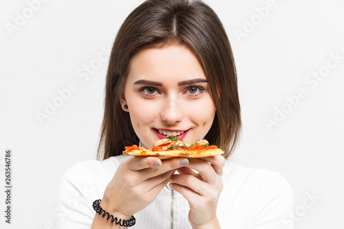 Mmm  so delicious  Dark haired pretty woman eats slice of Italian pizza  enjoys nice taste  isolated over white background.