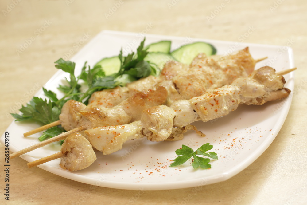 Baked chicken fillet on wooden skewers with cucumber and dill. Barbecue from pieces of chicken on wooden skewers. Baked chicken fillet on wooden skewers with cucumber and dill. Barbecue from pieces of chicken on wooden skewers.
