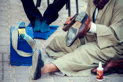 Man cleaning and polishing shoes in the street of Egypt
