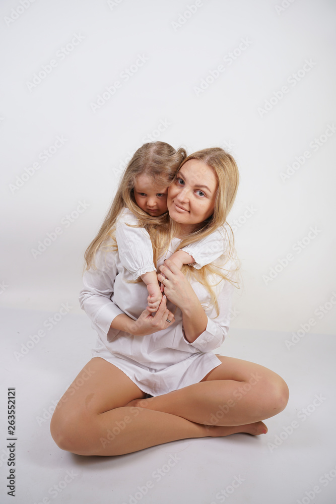 real family of caucasian mother and daughter in white shirts in the studio background real family of caucasian mother and daughter in white shirts in the studio background