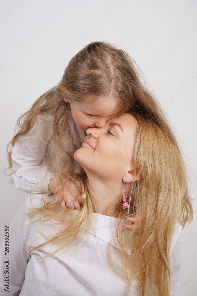 real family of caucasian mother and daughter in white shirts in the studio background real family of caucasian mother and daughter in white shirts in the studio background