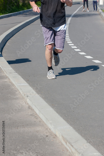Runner's legs. The athlete runs along the city road. Muscle work.