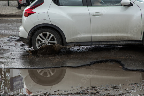 Car tyre about to pass through large pothole full of water photo