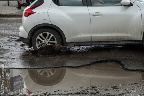 Car tyre about to pass through large pothole full of water