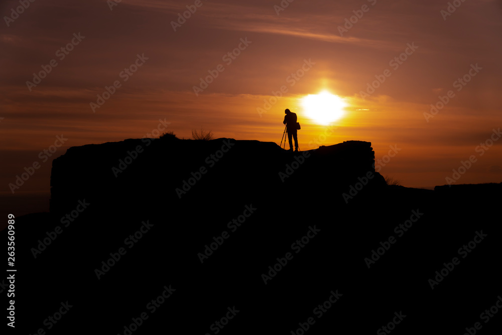 Silhouette of a photographer who shoots a sunset, on top of castle at sunset background.