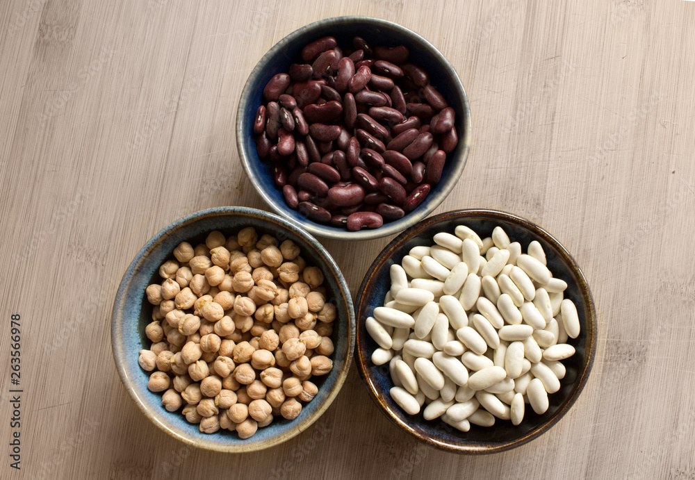 Chickpeas, red beans and white beans in ceramic bowls. Top view.