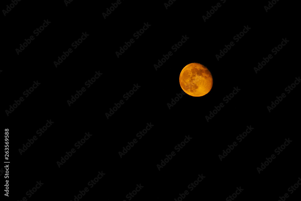 Wanning gibbous yellow moon in the black sky.